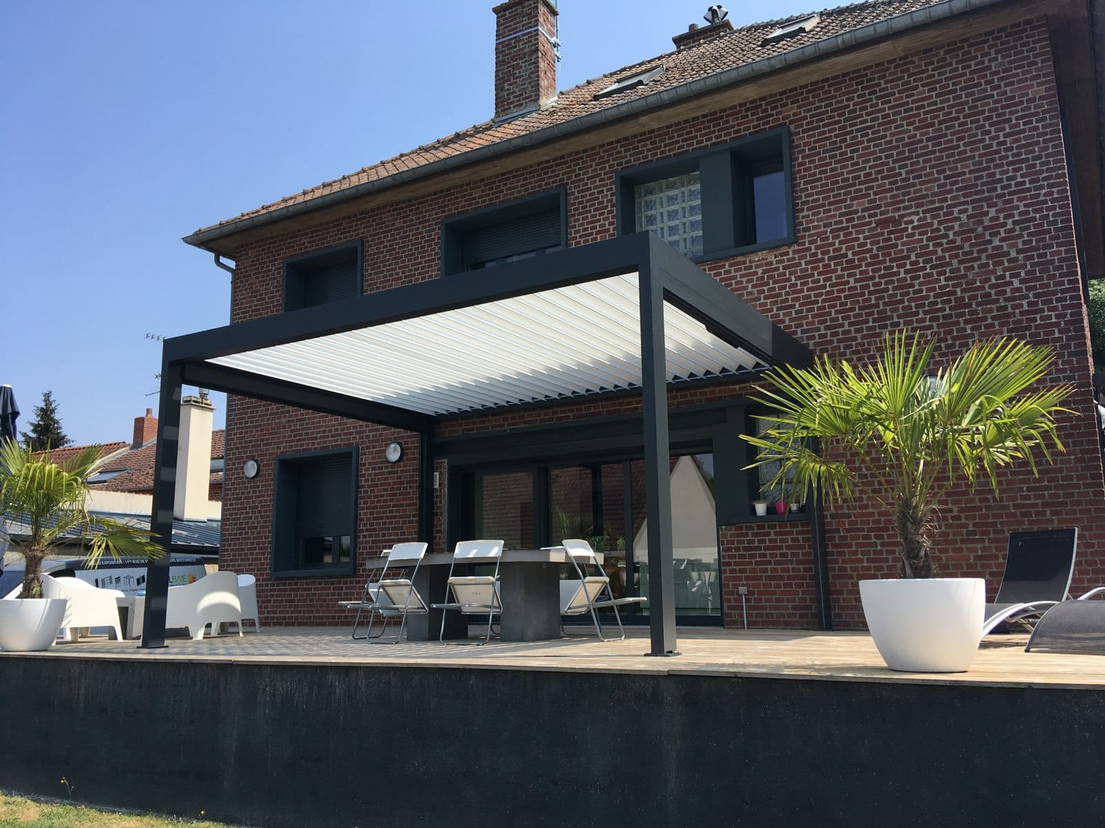 Pergola bioclimatique IZI Marquises sur terrasse, lames ondulées orientables