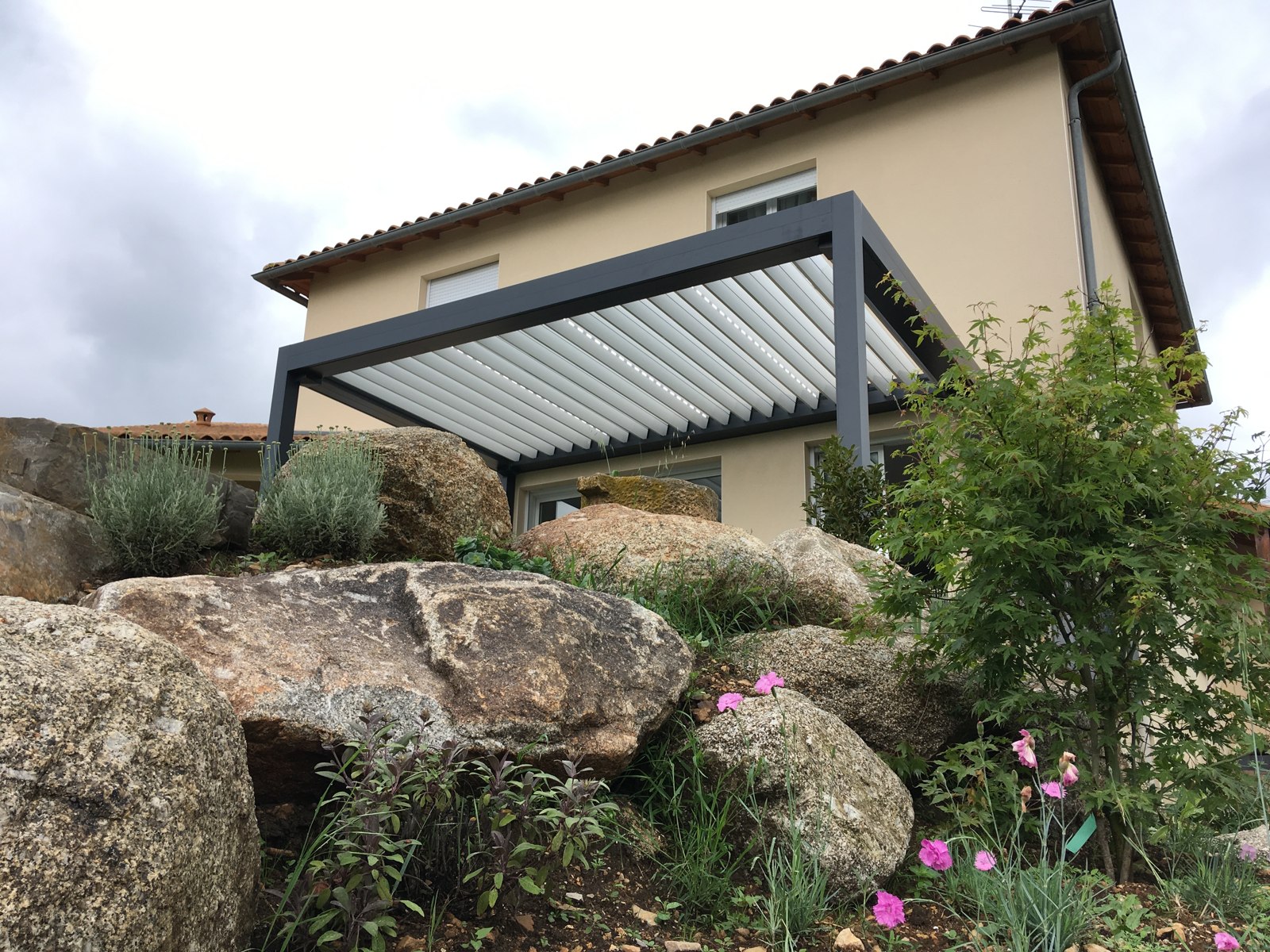 Pergola Open'R² de Marquises installée sur une terrasse, lames partiellement rétractées