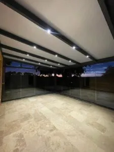 Abri de terrasse Climalux Skylux avec spots LED intégrés et parois vitrées — réalisation Top Fermetures