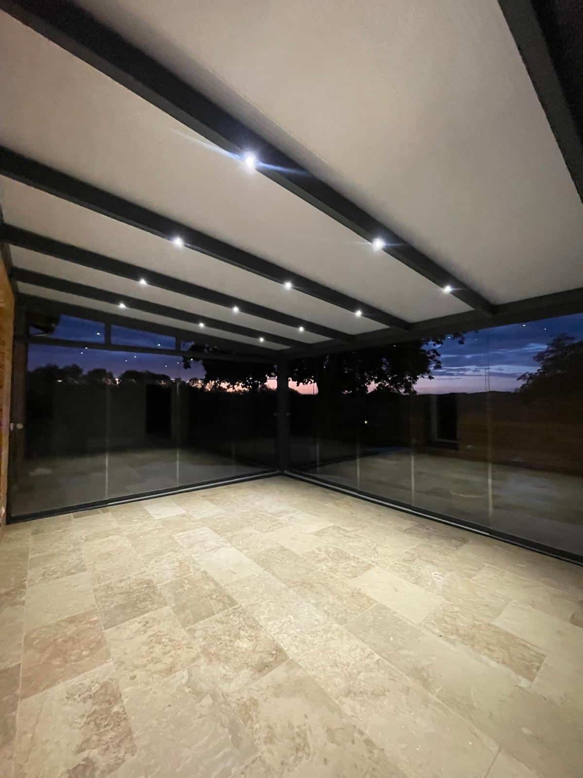 Abri de terrasse Climalux Skylux avec spots LED intégrés et parois vitrées — réalisation Top Fermetures